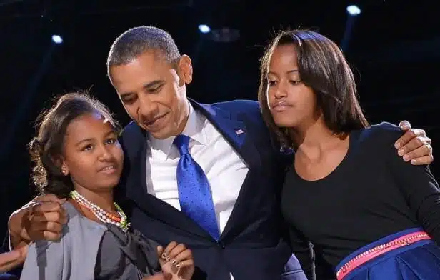 Barack Obama avec ses filles Malia et Sasha, souriants, lors d'un événement public