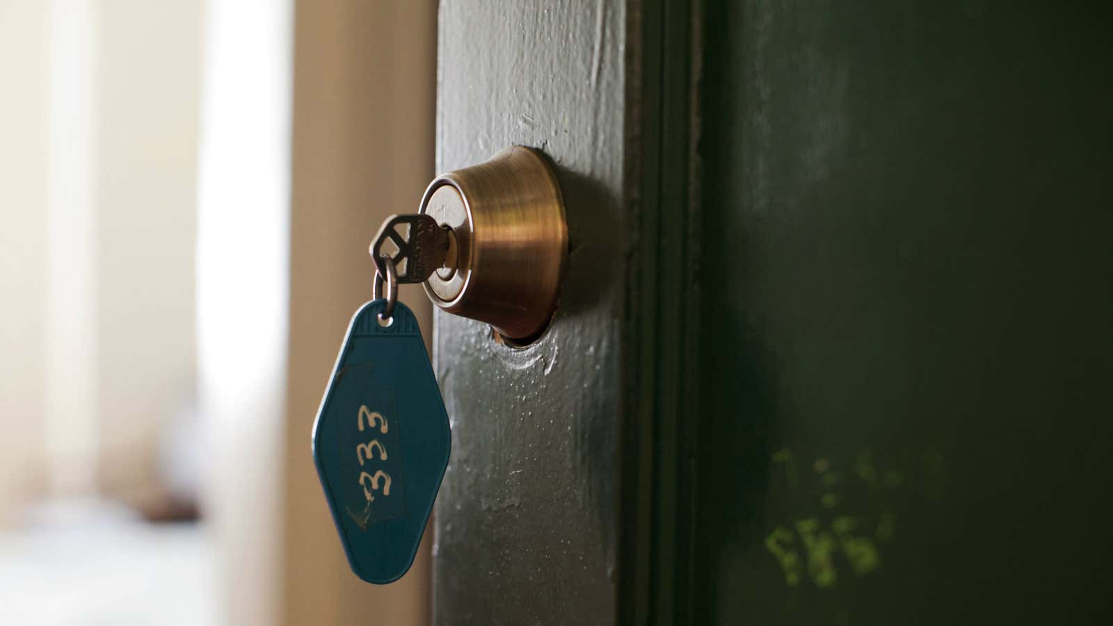 Clé dans une serrure avec en arrière-plan une maison la nuit