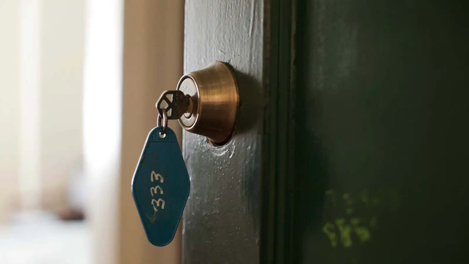 Clé dans une serrure avec en arrière-plan une maison la nuit