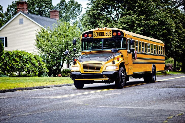 Bus scolaire avec un capot noir dans une ruelle 