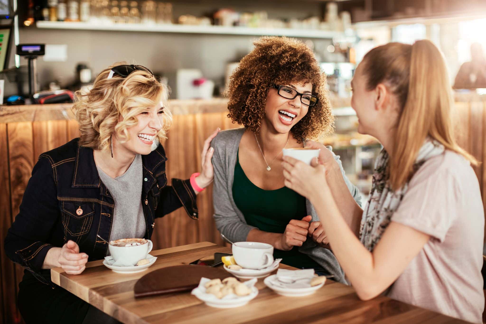 Groupe d'amies partageant un moment complice autour d'un café