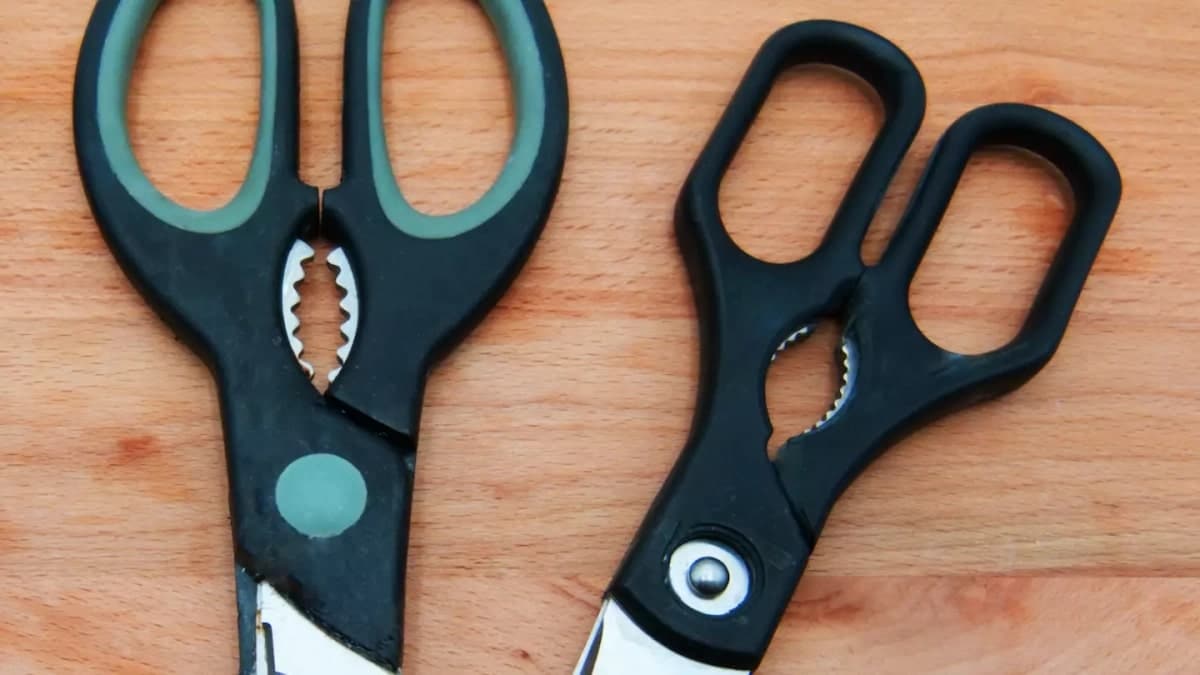 Ciseaux de cuisine posés sur un plan de travail en bois avec des herbes