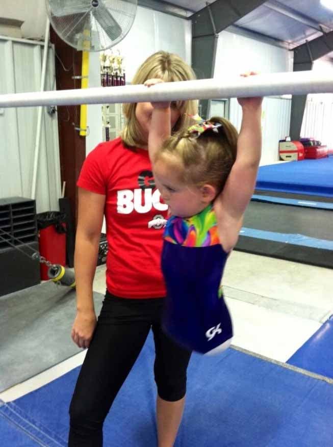 Paige s’aggripant à une barre de gymnastique