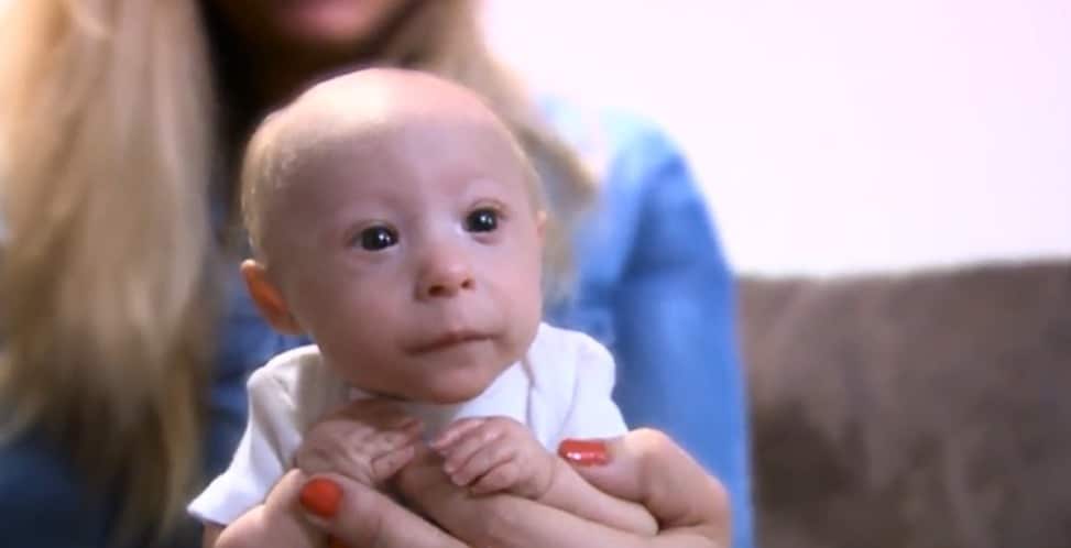 Mathieu, éveillé et calme, dans les bras d'un membre de sa famille