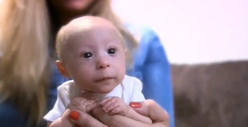 Mathieu, éveillé et calme, dans les bras d'un membre de sa famille