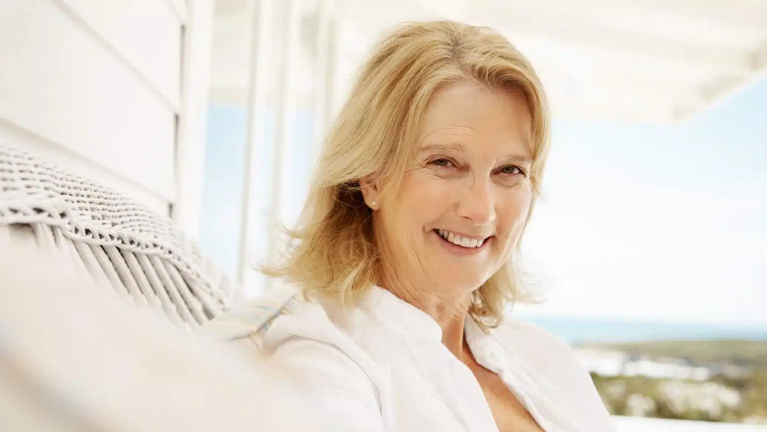 Femme souriante et sereine, les bras ouverts, devant un paysage lumineux