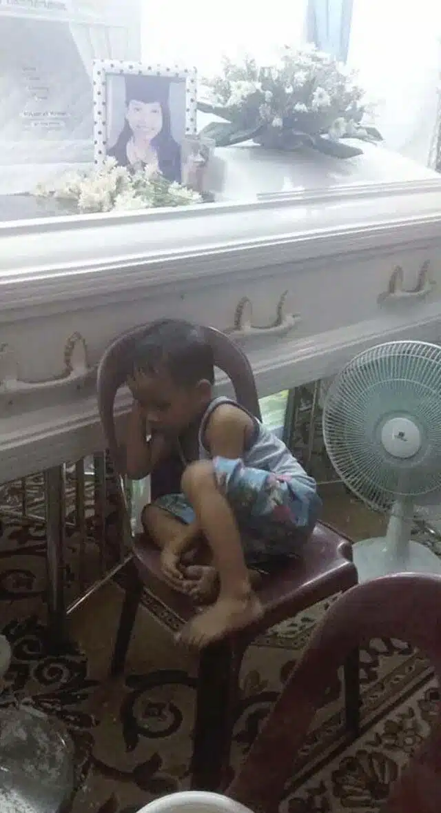 Un enfant blotti contre un cercueil