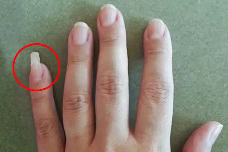 Homme utilisant son ongle long de l'auriculaire comme outil pratique