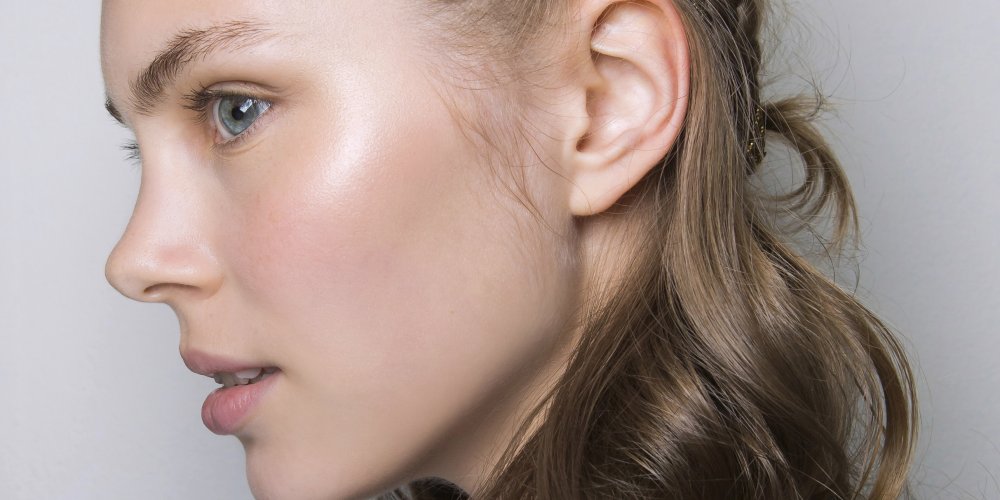 Femme appliquant un soin sur un visage au teint lumineux