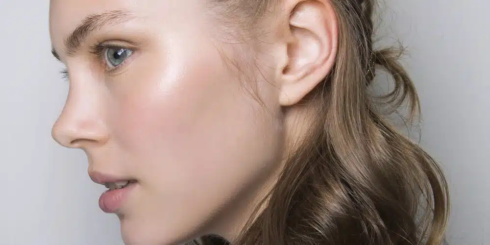 Femme appliquant un soin sur un visage au teint lumineux