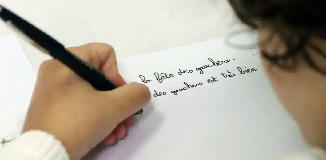 Enfant gaucher en train d'écrire, tenant son crayon avec une posture adaptée
