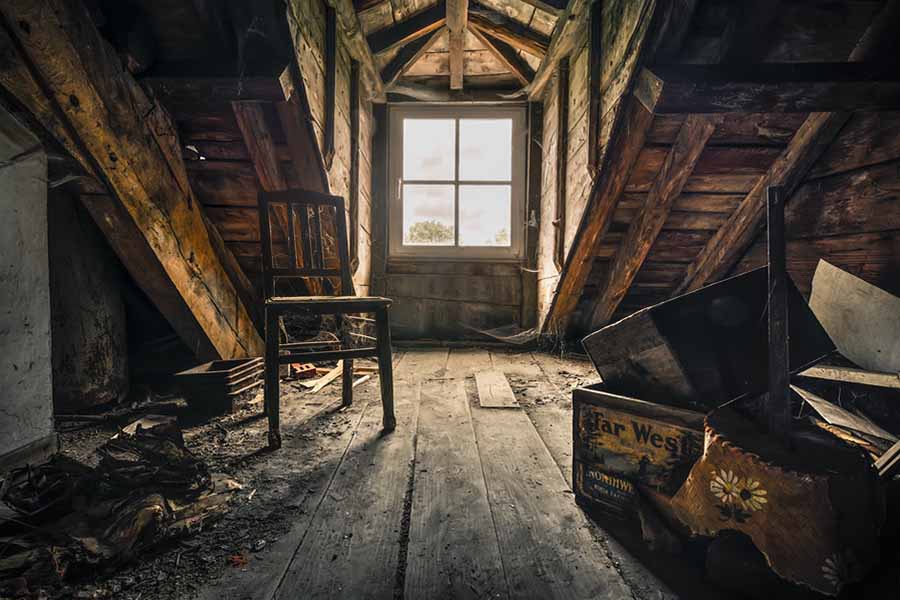 Intérieur d'un grenier ancien, avec des objets recouverts de poussière et une lumière tamisée