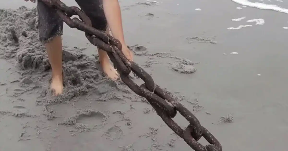 La vie d'un pauvre garçon change après qu'il a retiré une vieille chaîne rouillée qui dépassait du sable sur une plage isolée