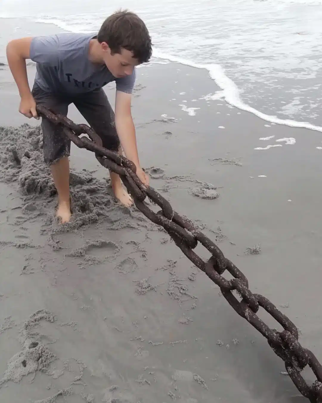 La vie d'un pauvre garçon change après qu'il a retiré une vieille chaîne rouillée qui dépassait du sable sur une plage isolée