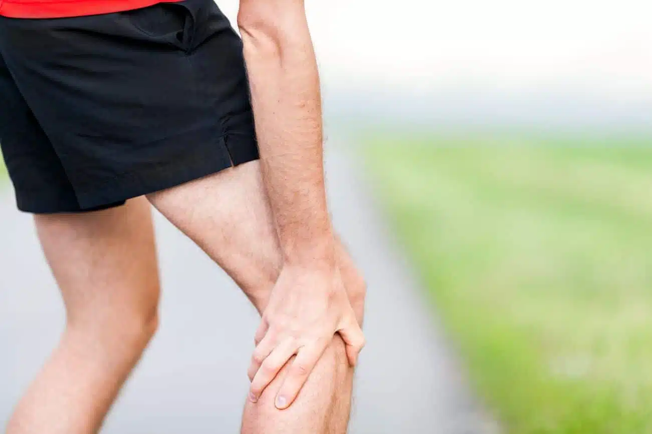 personne massant sa jambe après une crampe