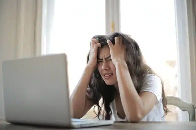 femme se tenant la tête devant son ordinateur