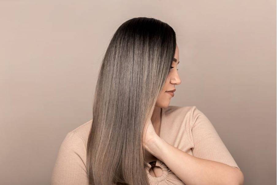Femme aux cheveux longs et lisses, tenant une bouteille d'huile végétale naturelle
